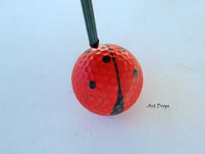 Schwarze Punkte auf einen Golfball malen