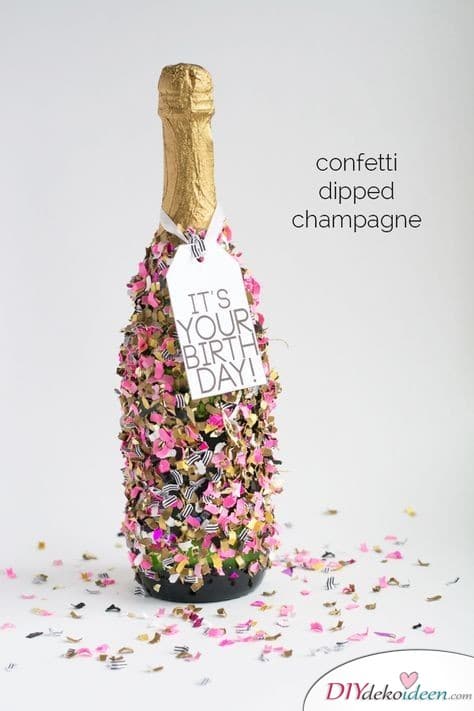Mit Konfetti beklebte Champagnerflasche als Geburtstagsgeschenk